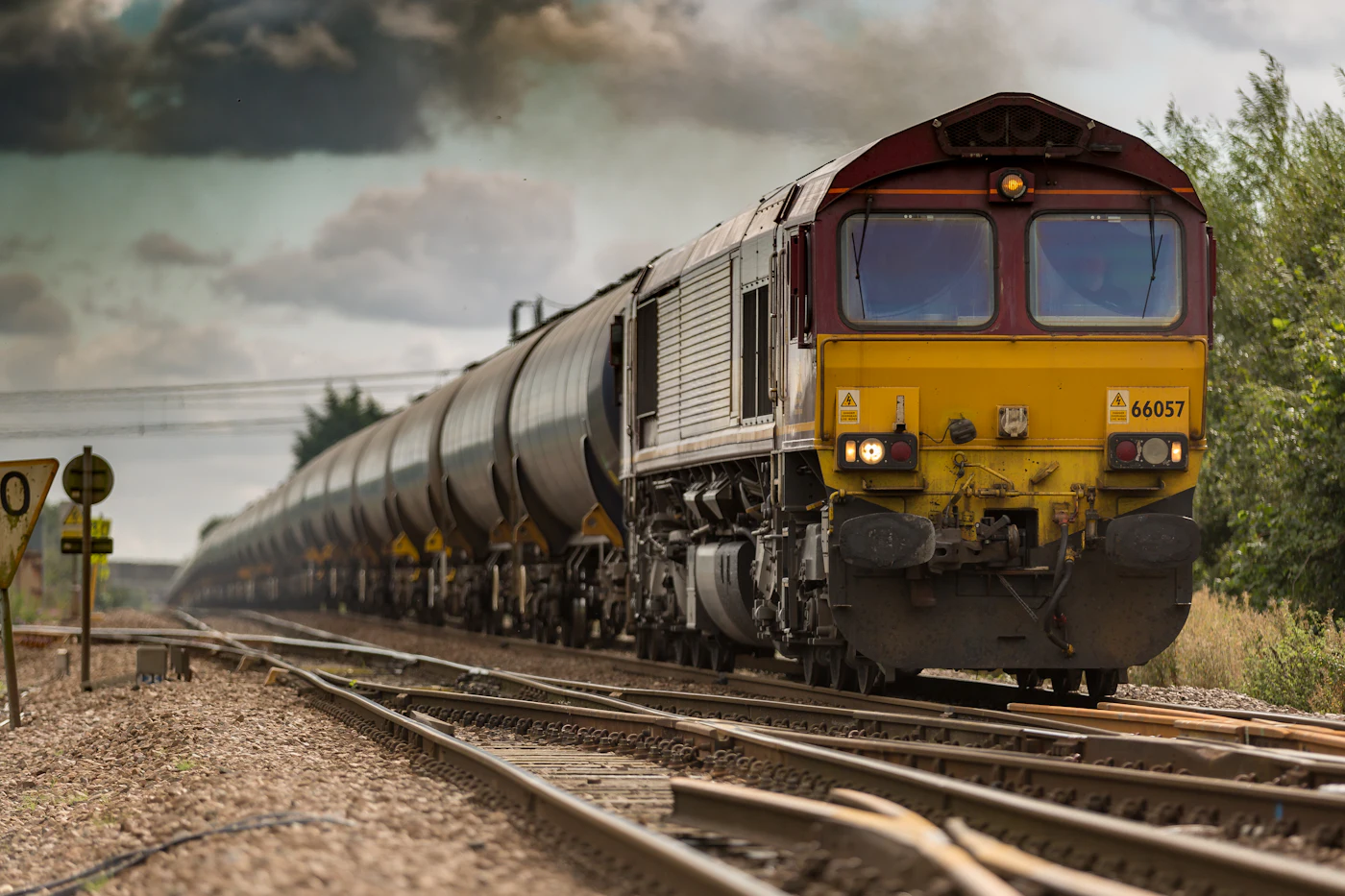 A freight locomotive pulling a line of tanker wagons along a rural railway