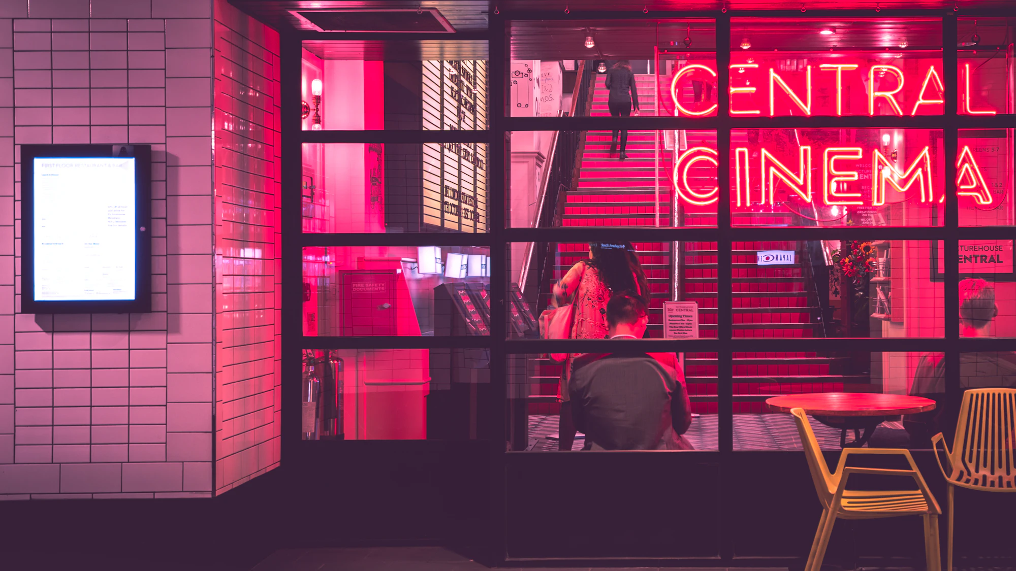 A neon-lit cinema entrance with a pink glowing sign at night