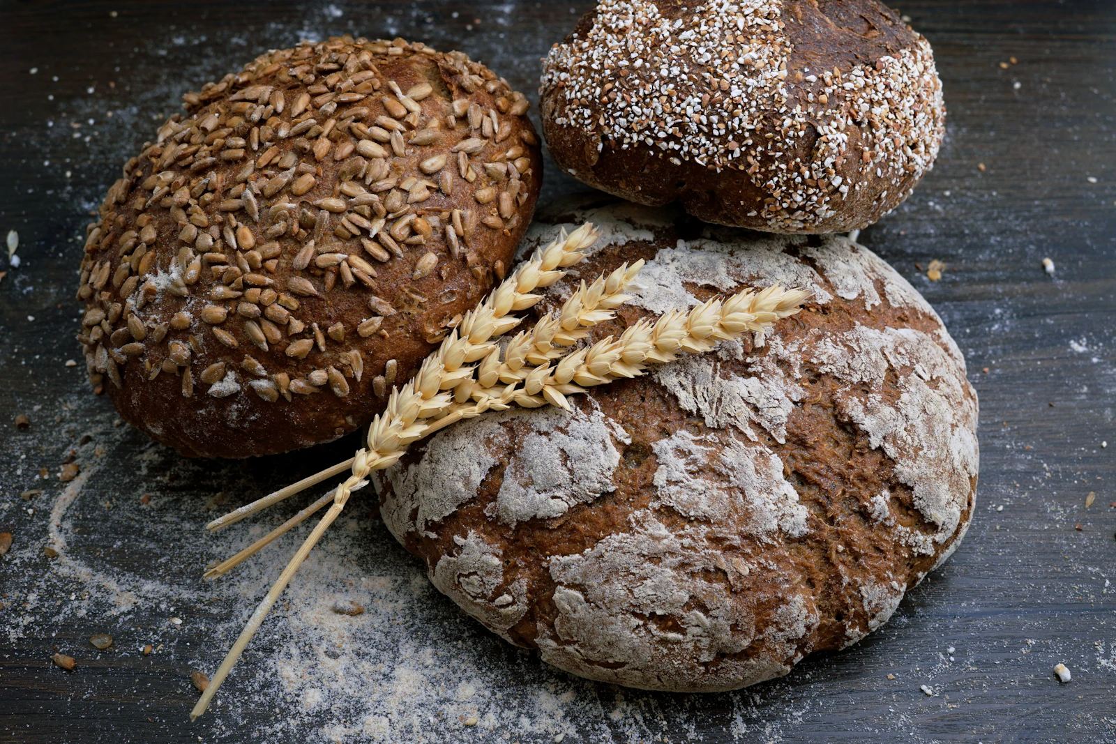 Rustic sourdough and seeded loaves with wheat stalks on a floured board