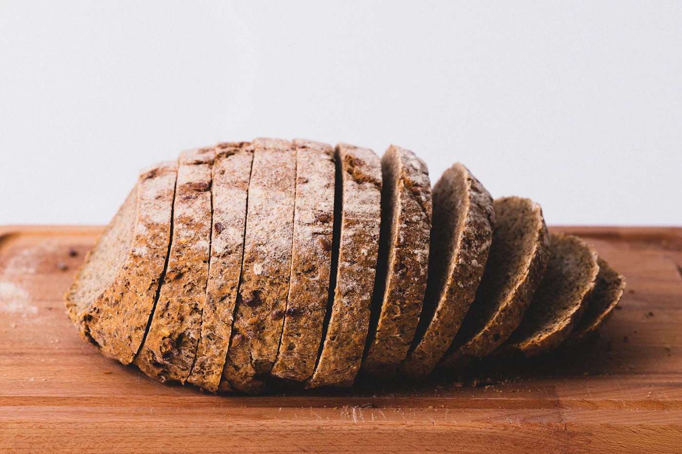 A rye loaf cut into slices on a wooden board showing its crumb