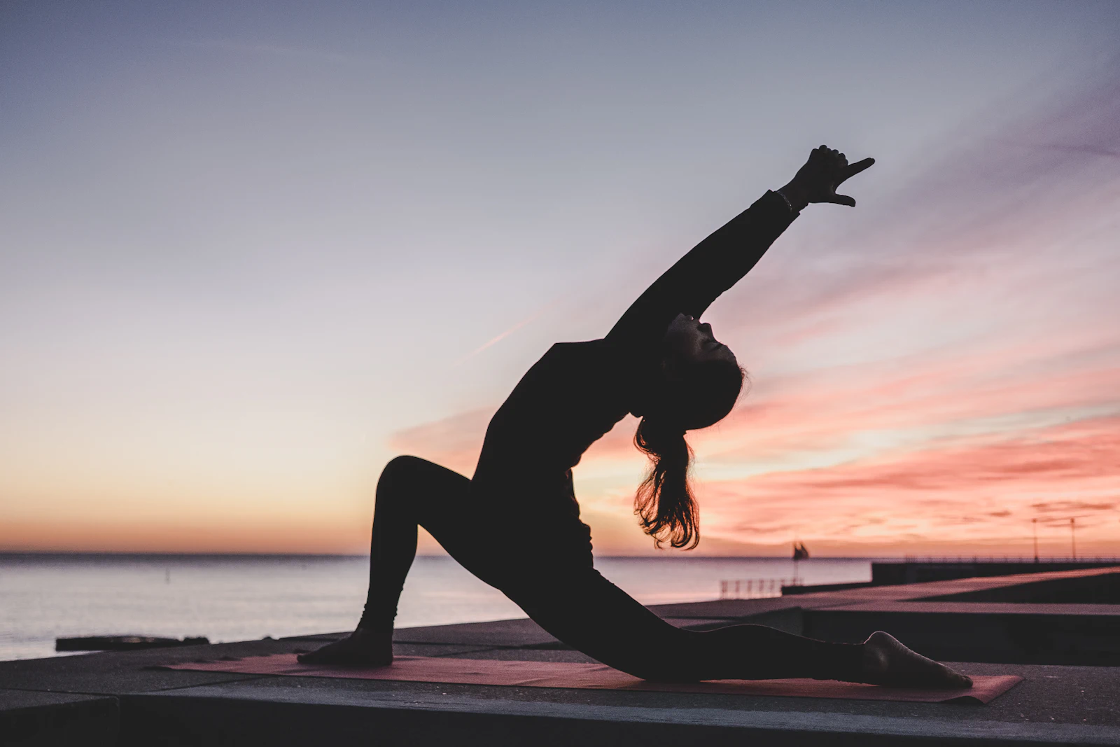 Silhouette of a woman holding a yoga pose against a glowing sunset sky