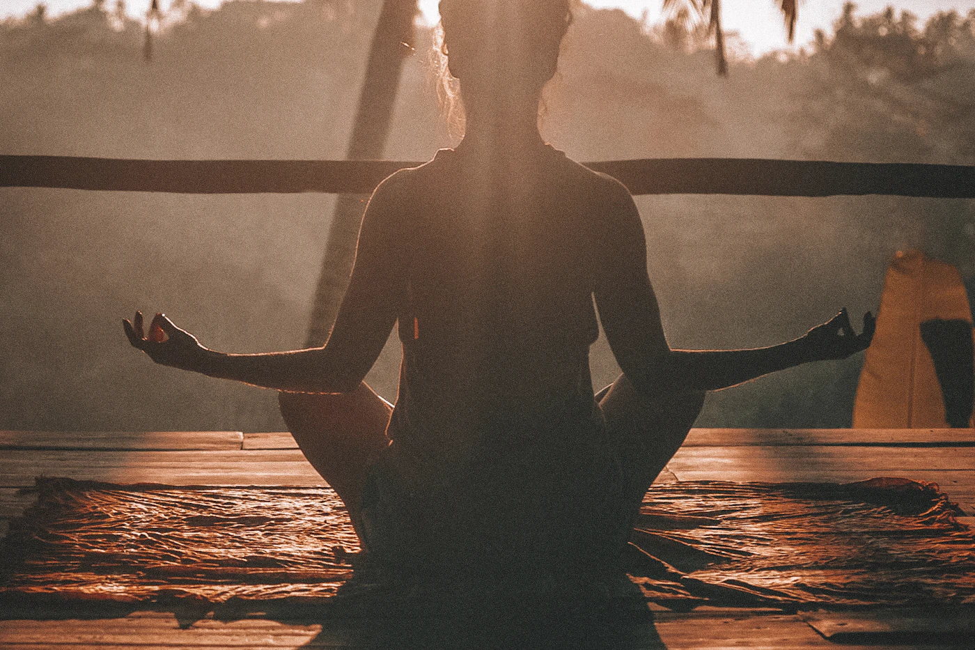 A person meditating cross-legged in warm morning sunlight