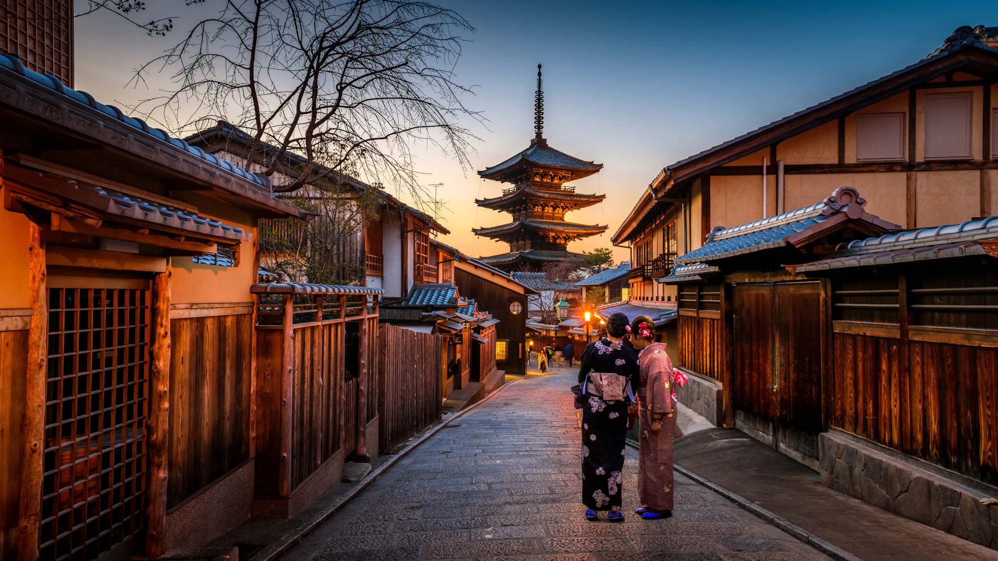 A traditional wooden street leading to a pagoda in Kyoto at sunset